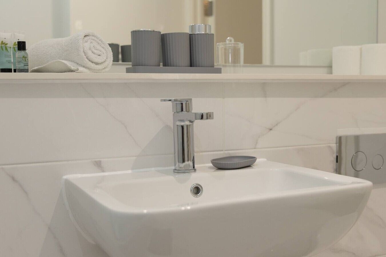Une salle de bain moderne avec un lavabo blanc, un robinet chromé et un miroir au-dessus.