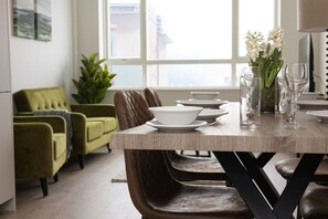 A dining area with a wooden table, chairs, and a window with a view. - Sapphire Court Flat 69 2-Bedroom for family corporate or business travel (Birmingham)