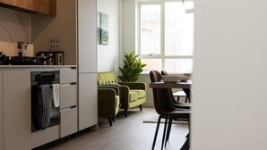 A modern kitchen with a dining area, a green sofa, and a large window. - Sapphire Court Flat 69 2-Bedroom for family corporate or business travel (Birmingham)