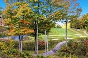 A golf course with a water body, trees, and a pathway. - Happy Place at Cedar River (Bellaire)