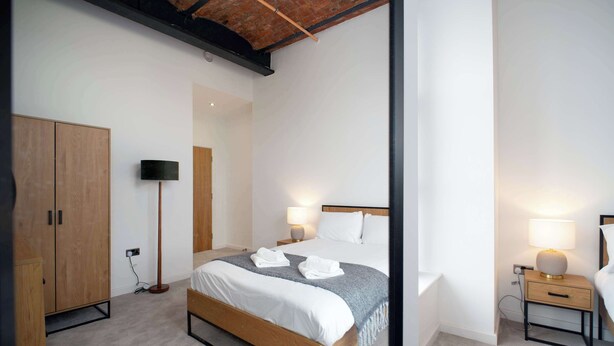 Ein Schlafzimmer mit Bett, Nachttischen, einer Stehlampe und einem Kleiderschrank.