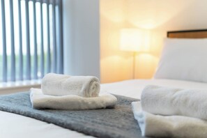 A neatly made bed with rolled white towels and a stone tray. - Contemporary 2 Bedroom Apartment in Manchester (Manchester)