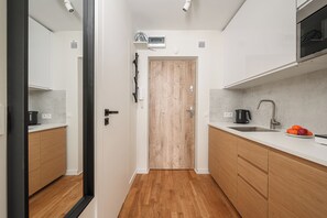 Eine moderne Küche mit Holzschränken, einer weißen Arbeitsplatte, einem Spülbecken und einer Mikrowelle.