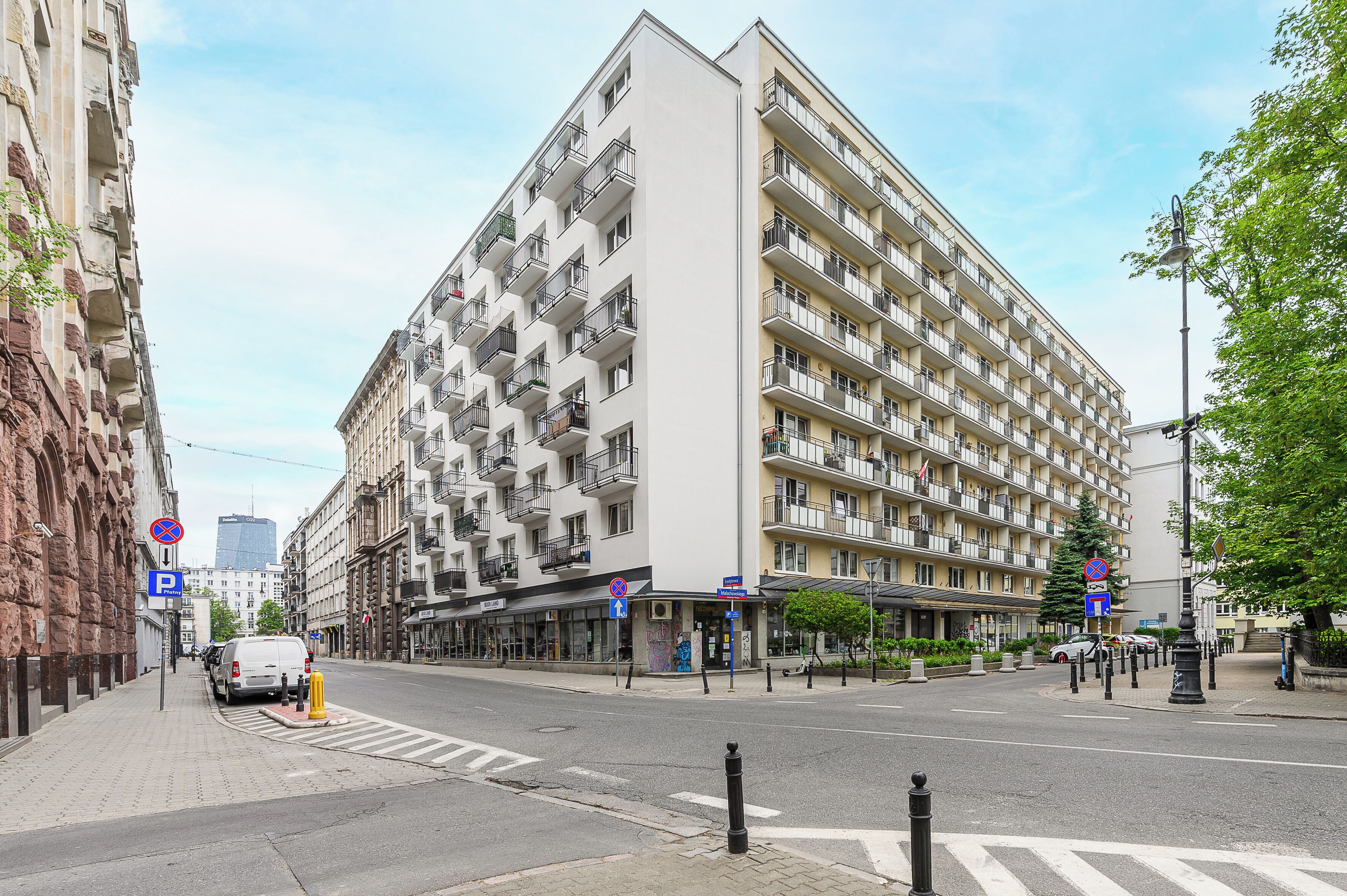 Monikerroksinen hotelli, jossa on parvekkeet, pysäköintikyltti ja jalankulkijoiden suojatie.
