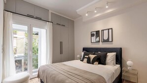 A bedroom with a bed, a sliding door to a balcony, and a wall-mounted light fixture. - Calming 1BR Apartment Acropolis view (Athens)