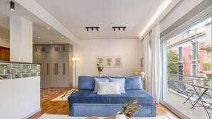 A modern living room with a blue sofa, a small wooden coffee table, and a view of the outside balcony. - Calming 1BR Apartment Acropolis view (Athens)