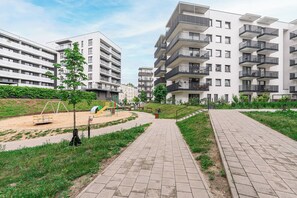 A residential building with multiple floors, balconies, and a paved walkway. - Lumina Apart nearManufartura and Parking (Łódź)