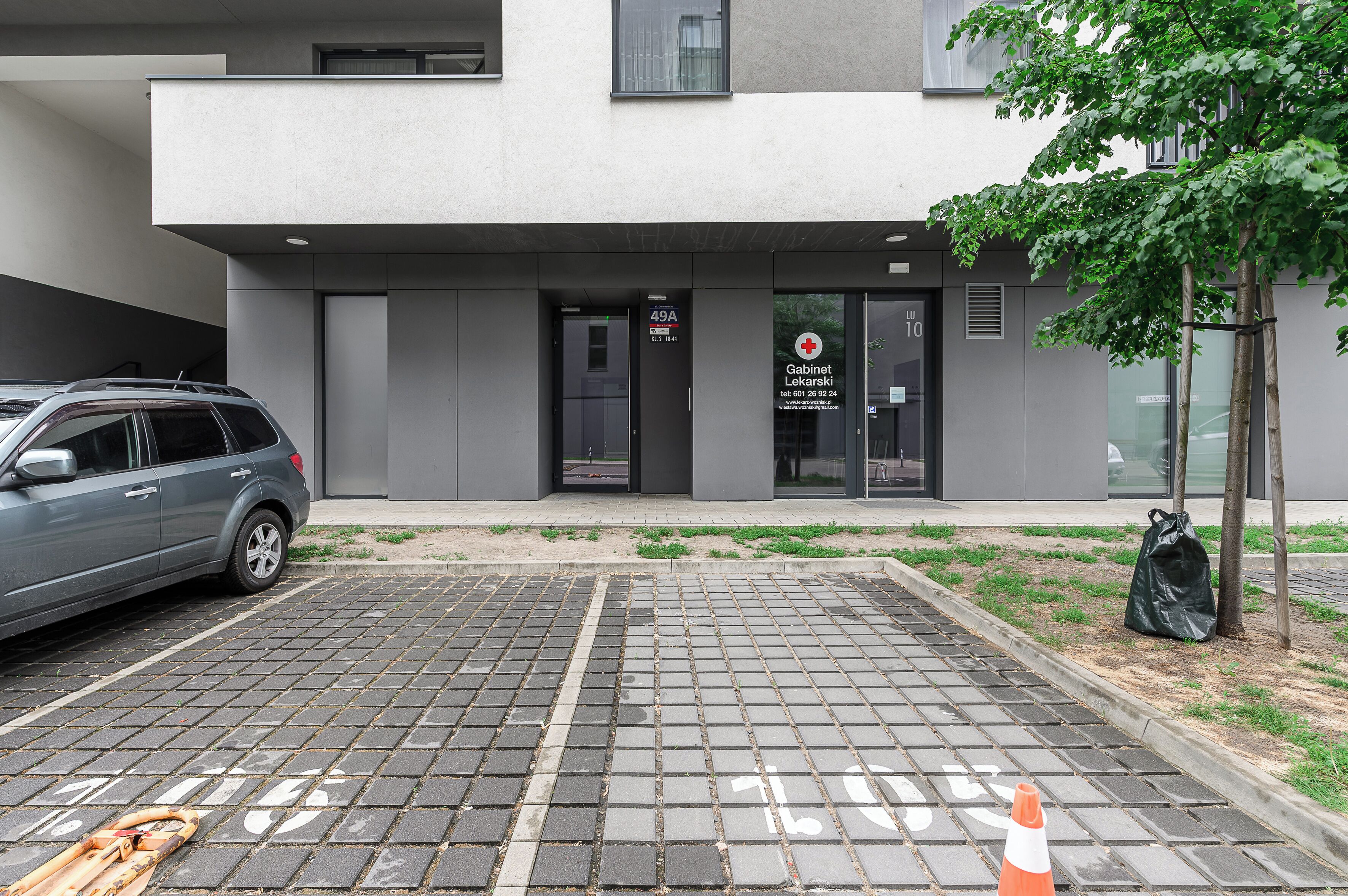 Een modern gebouw met een bordje voor 'Cabinet Lekarski' en een geparkeerde auto.