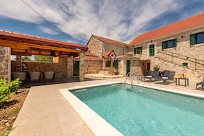 A swimming pool with lounge chairs, a stone building with a red-tiled roof, and a stone staircase. - Villa Zvonimir Zadarvillas (Promina)
