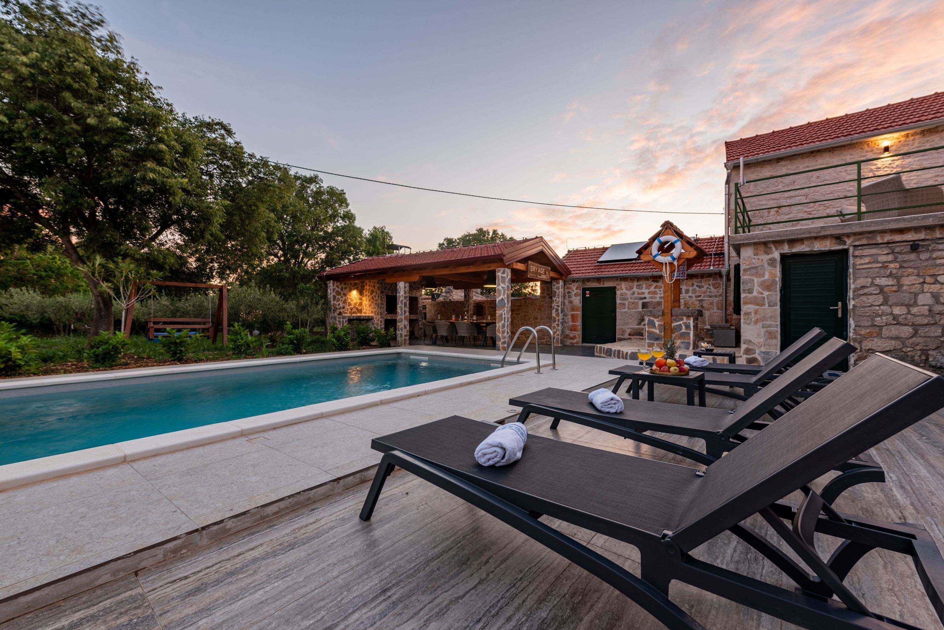 A poolside area with lounge chairs, a stone building, and a clear sky.