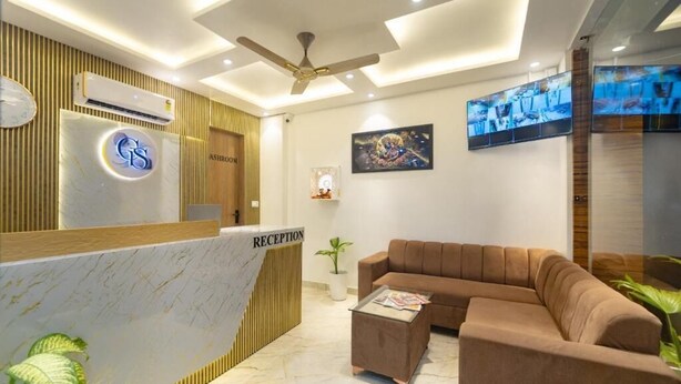 Una zona de recepción con mostrador de mármol, ventilador de techo, sofá y televisor en la pared.