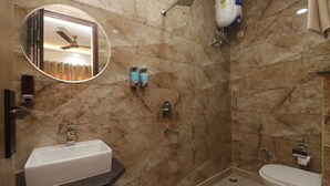 Un baño con pared de mármol, un lavabo, un inodoro, una ducha y un ventilador de techo.
