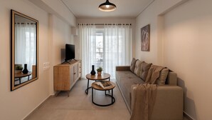En moderne stue med sofa, sofabord, fjernsyn og et spejl.