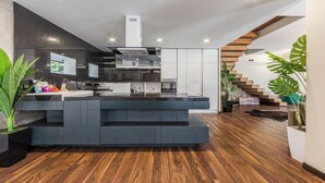 Une cuisine moderne dotée d’un îlot central, d’appareils électroménagers intégrés et d’un escalier menant à un niveau supérieur.