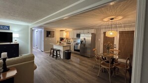 Une cuisine moderne dotée d’un îlot central, d’appareils électroménagers en acier inoxydable et d’un coin repas avec des chaises en bois.