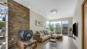 Un salon moderne avec un mur en pierre, une cheminée, un canapé, une table basse et un téléviseur.
