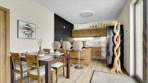 Une cuisine moderne avec des meubles en bois, un réfrigérateur noir et un coin repas comprenant des chaises et une table en bois.