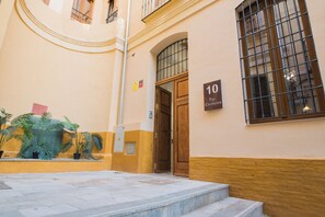A building entrance with a wooden door, a number sign, and potted plants. - Authentic Studios Alzazaba (Malaga)