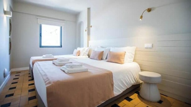Hotellihuone, jossa on kaksi sänkyä, ikkuna, yöpöytä ja wc.