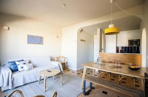 Ein modernes Wohnzimmer mit Sofa, Couchtisch und Essbereich mit Stühlen und Holztisch.