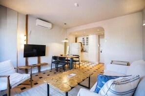 Ein modernes Wohnzimmer mit Flachbildfernseher, Esstisch und Sofa.