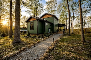 Une maison à deux étages avec une allée en gravier et un porche en bois.