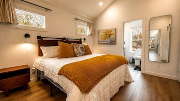 A bedroom with a bed, bedside table, and a large mirror.