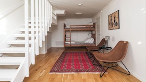 A room with a bunk bed, a chair, a small table, a red patterned rug, and a staircase. - Brunkulla - Tänndalen (Tänndalen)