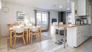 A modern kitchen with white cabinetry, a wooden dining table, and pendant lighting. - Brunkulla - Tänndalen (Tänndalen)
