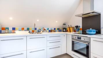 A modern kitchen with white cabinets, a built-in oven, and a colorful backsplash.