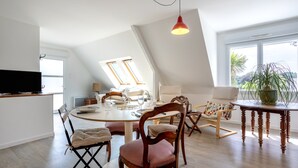 Un coin repas avec une table ronde, des chaises et un téléviseur posé sur un meuble.