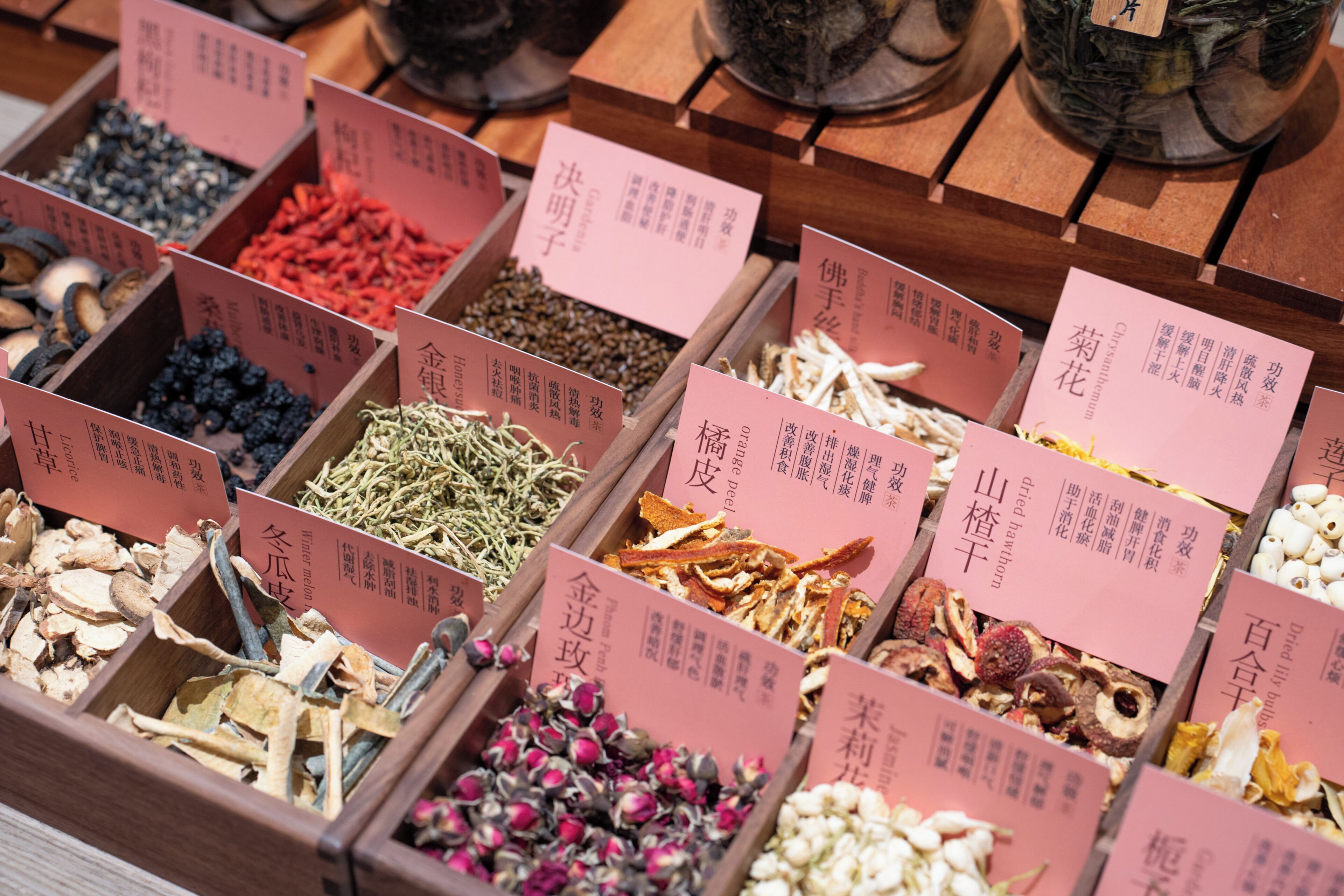 Wooden boxes filled with various dried herbs and spices, each labeled with text.