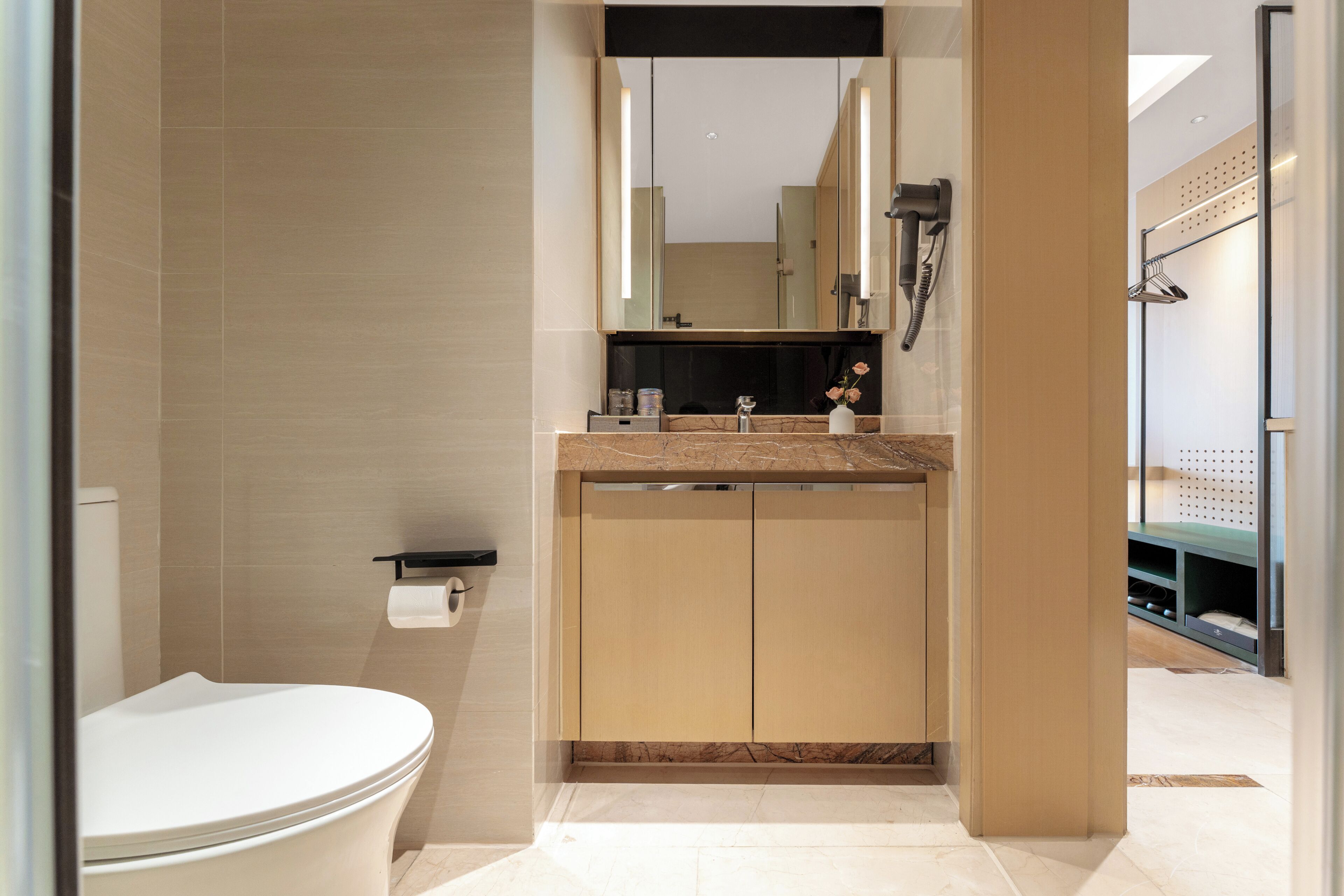 A modern bathroom with a toilet, sink, mirror, and shower area.