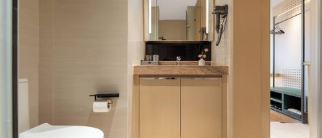 A modern bathroom with a toilet, sink, mirror, and shower area.