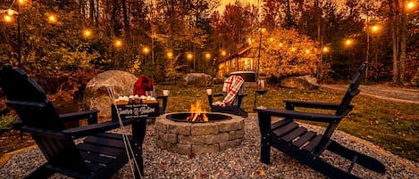 An outdoor seating area with Adirondack chairs, a stone fire pit, and a snack station.