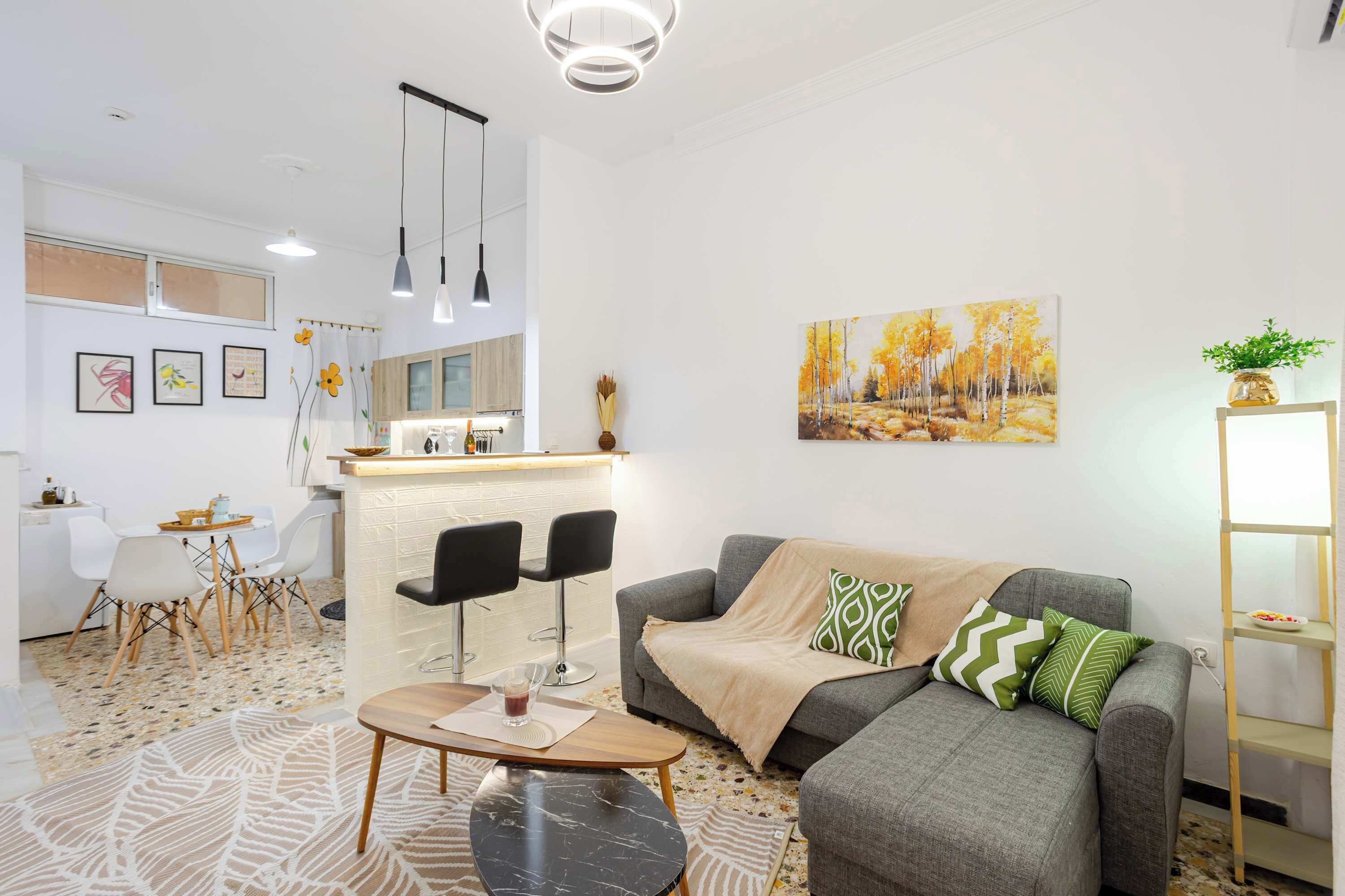 A modern living room with a grey sofa, a coffee table, and a dining area with a white table and chairs.
