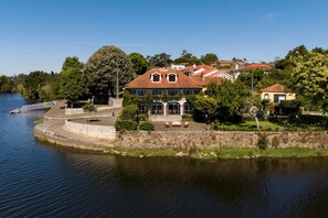 Une propriété située au bord de la rivière, comprenant une grande maison, un belvédère et un mur en pierre.