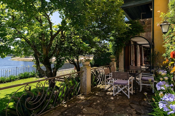 A terrace with stone flooring, metal railings, and outdoor seating.