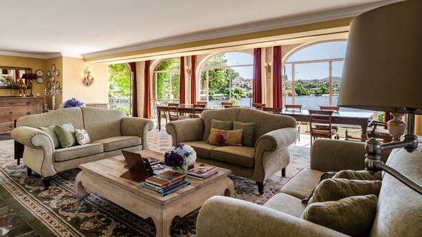 A spacious living room with two sofas, a coffee table, and a dining area with a view of a lake.