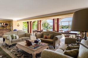 A spacious living room with two sofas, a coffee table, and a dining area with a view of a lake.