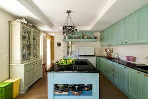 A kitchen with a central island, a cabinet with glass doors, and a hanging light fixture.