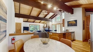A modern kitchen with wooden beams, a dining area with a marble table, and a bear artwork on the wall. - Upscale Tahoe Townhome Near Incline w Fireplace (Incline Village)