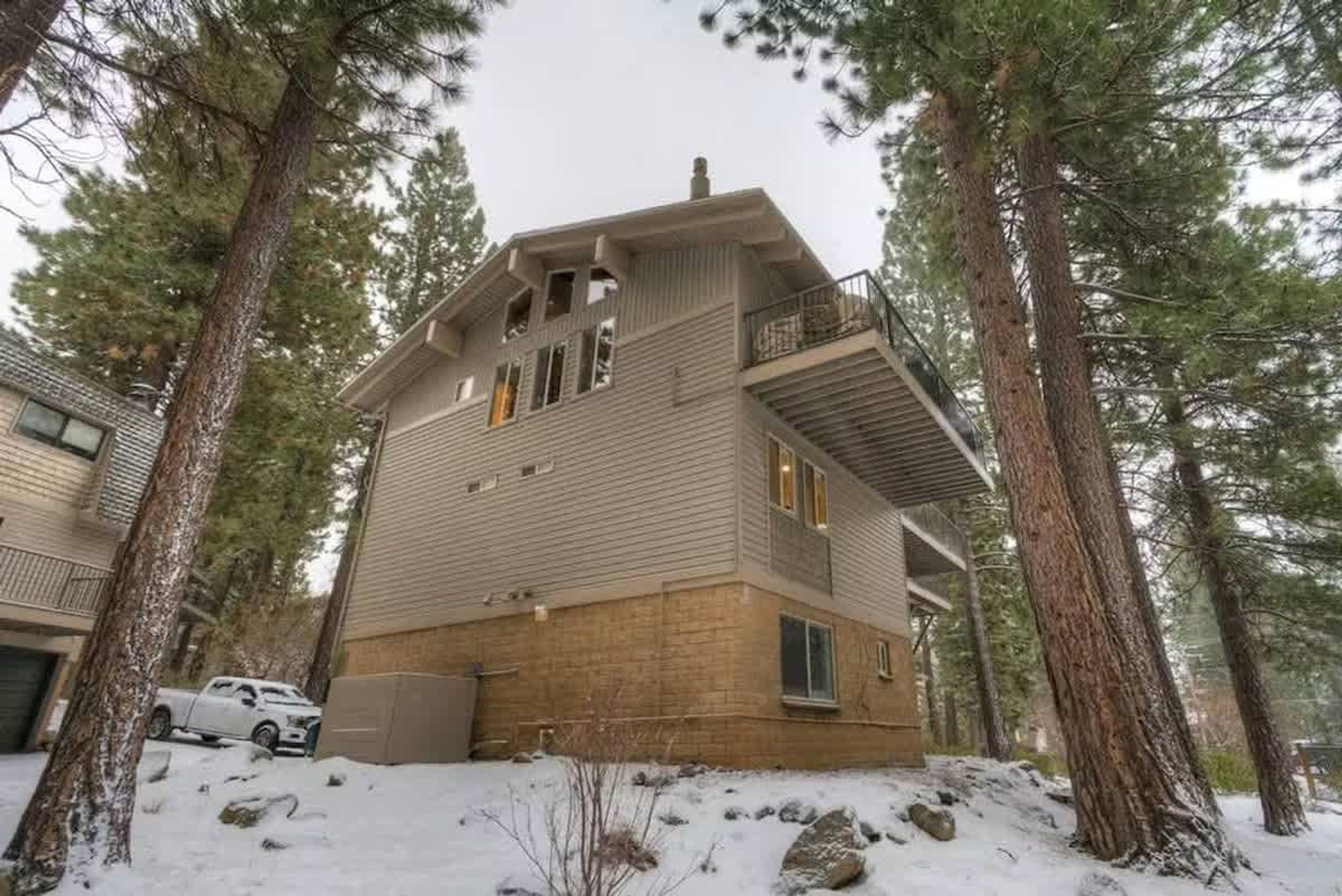 A two-story building with a balcony, surrounded by trees and snow.