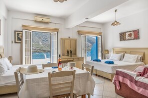 A hotel room with two beds, a dining table, and a view of the sea. - Katerina's Studio '1' with Sea View and Private Balcony (Arginonta)