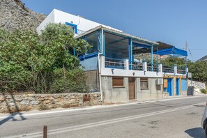 A coastal building with a balcony, a stone wall, and a clear sky. - Katerina's Studio '1' with Sea View and Private Balcony (Arginonta)