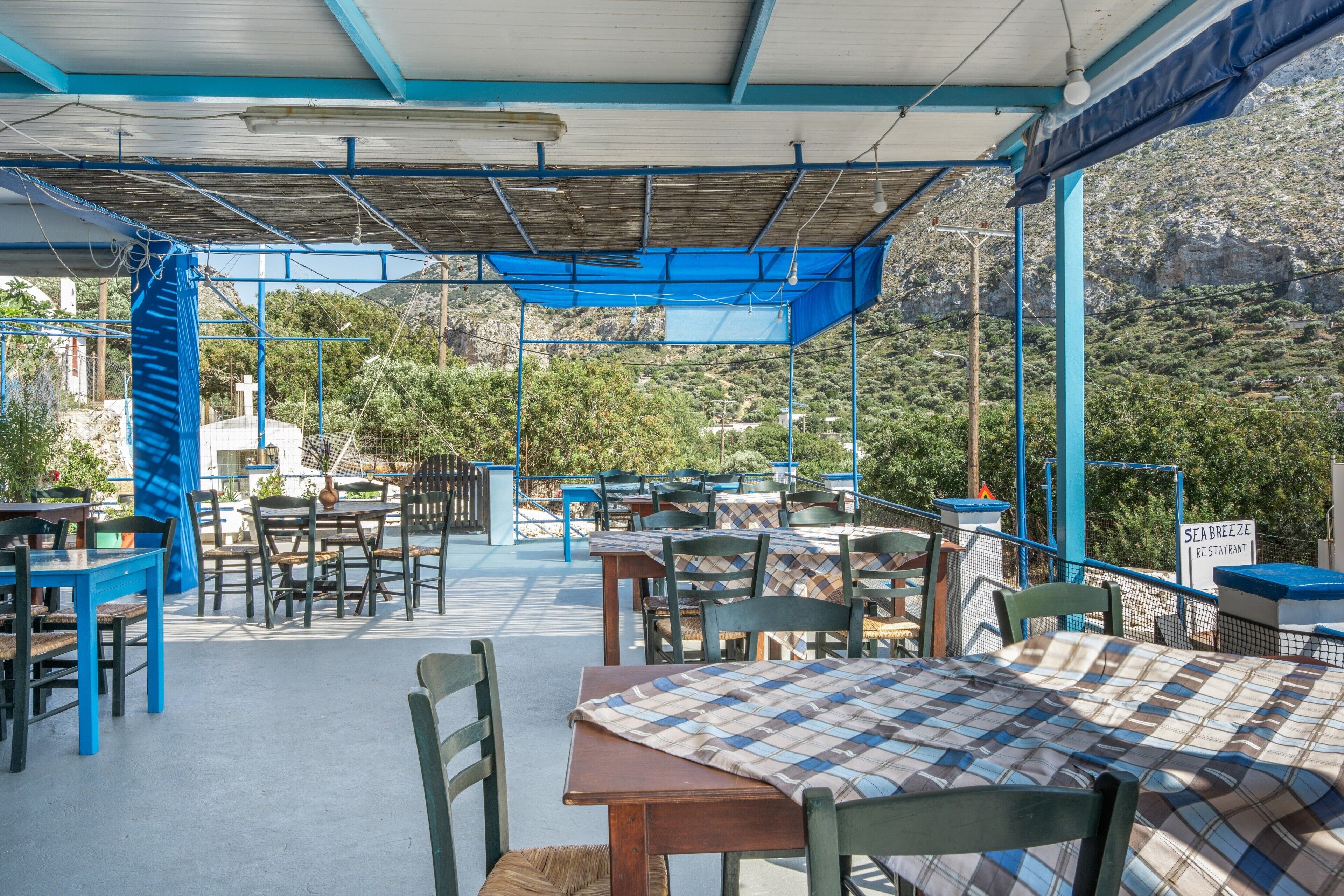 Un espace de restauration en plein air avec des tables et des chaises, une partie abritée et une vue sur un paysage montagneux.