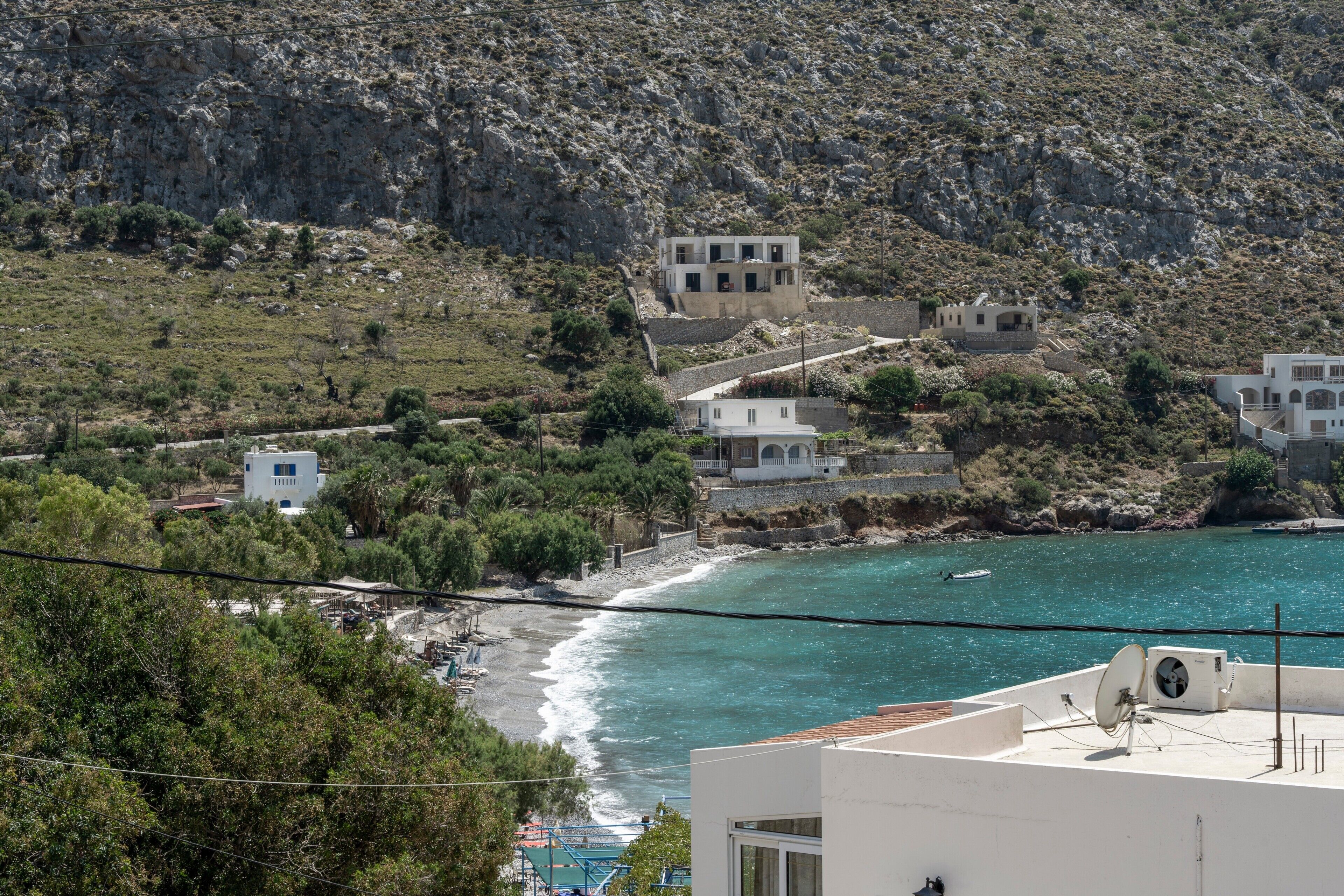 Un village côtier caractérisé par un paysage rocheux, des bâtiments blancs et une vue sur la mer.