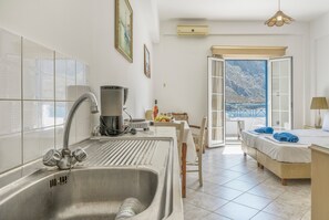 A modern kitchen with a stainless steel sink, a coffee maker, and a dining area with a table and chairs. - Katerina's Studio '2' with Sea View and Private Balcony (Arginonta)