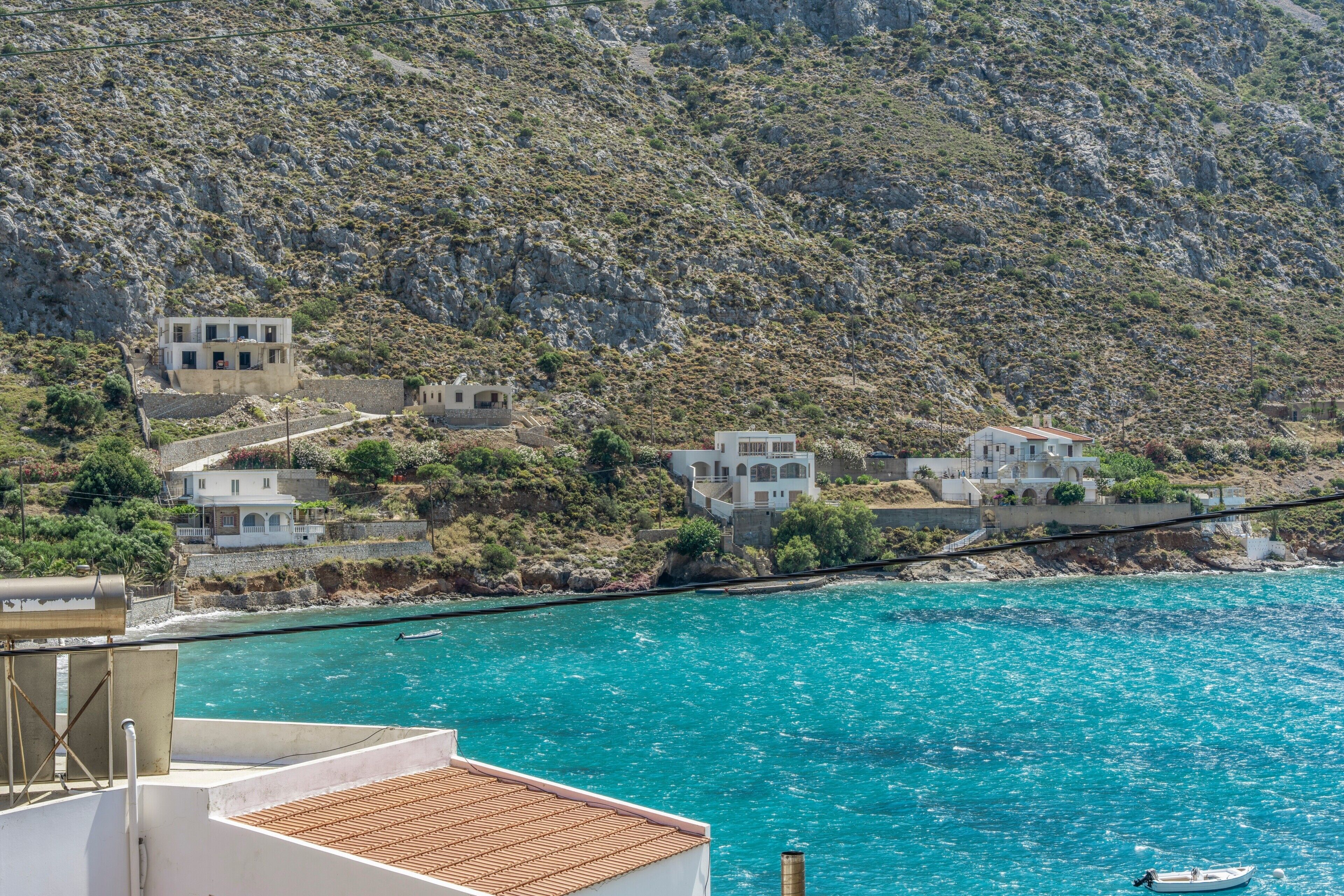 A coastal village with buildings along the hillside and a boat in the water.