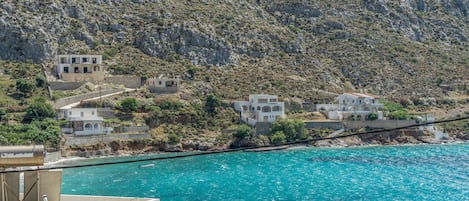 A coastal village with buildings along the hillside and a boat in the water.
